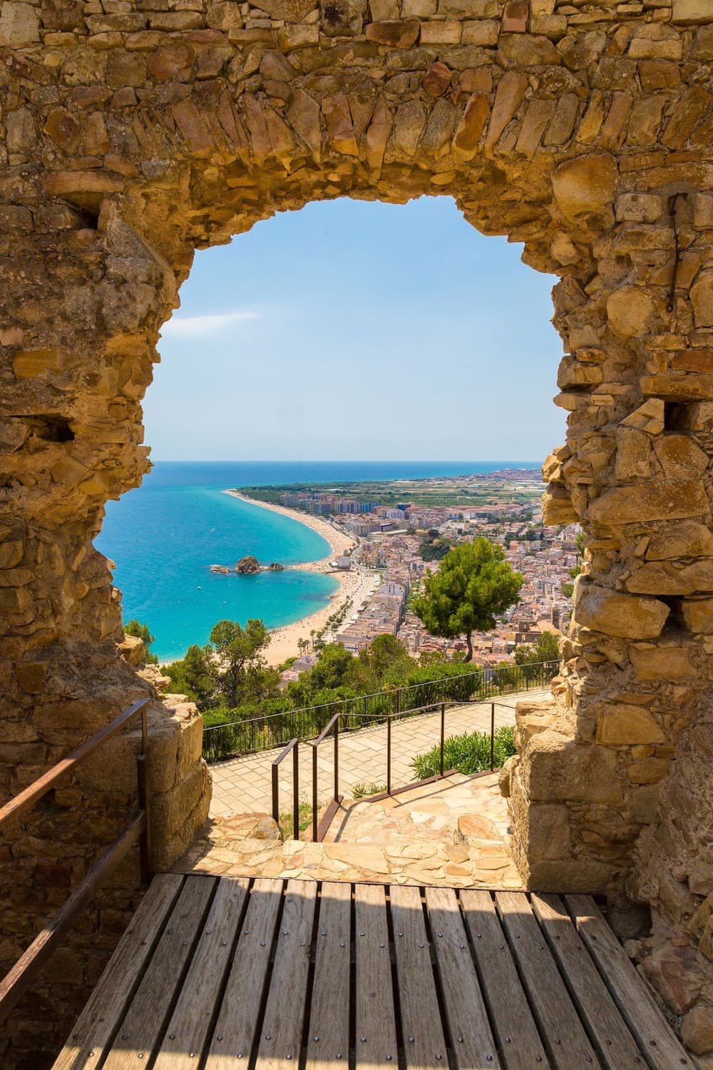 Panoramablick auf den Strand von Blanes durch ein Steintor der Burg San Juan