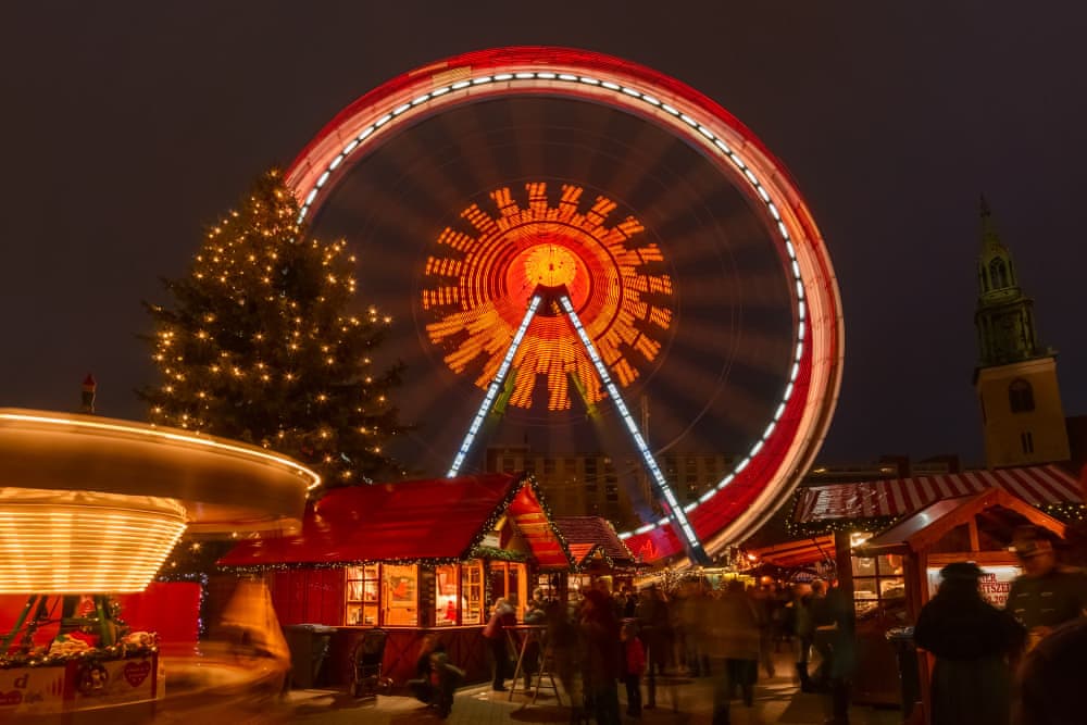 Noel pazarı dönme dolabı ve ışıklı yılbaşı ağacı, gece manzarası.