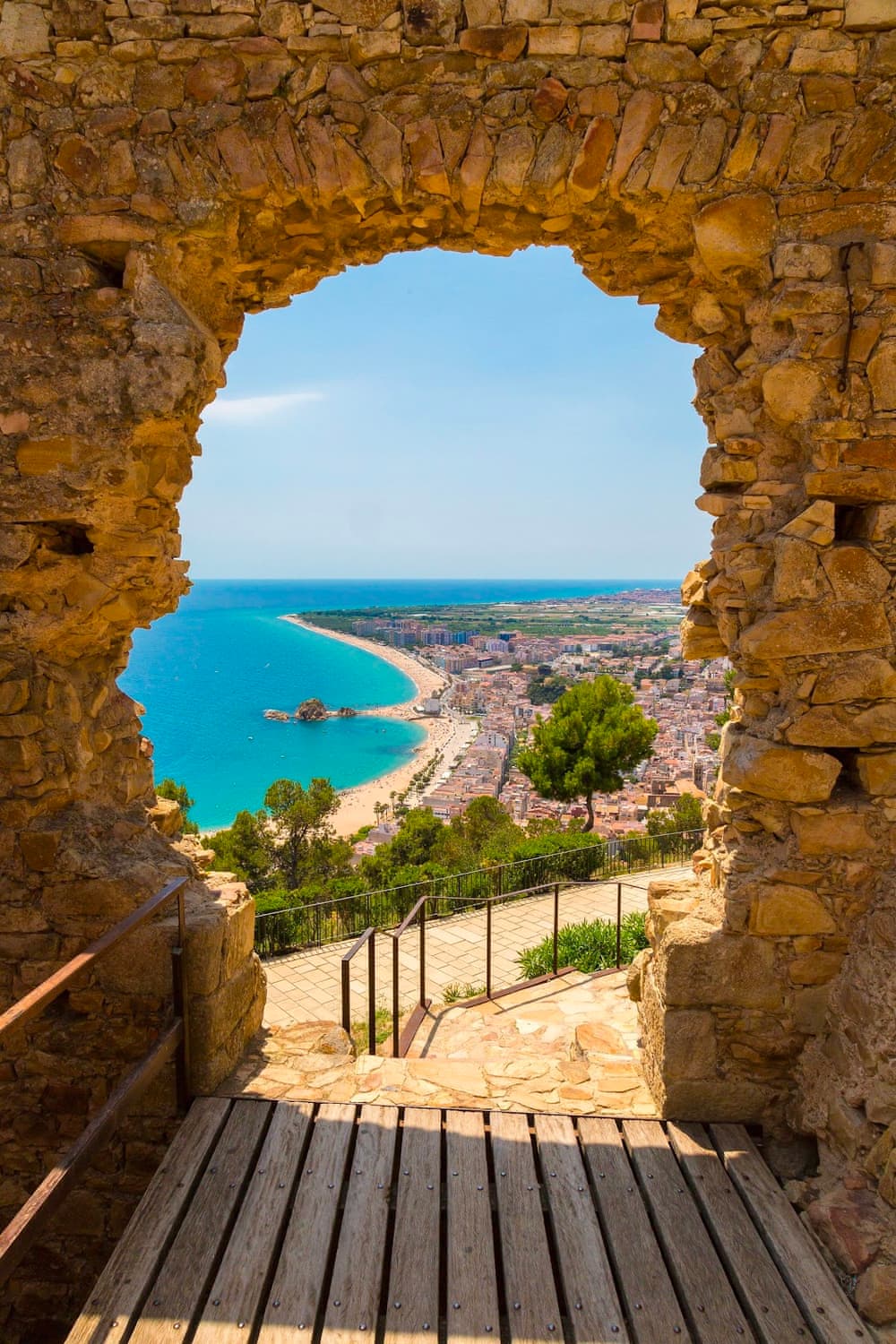 Вид на пляж Бланес через ворота замка Сан-Хуан